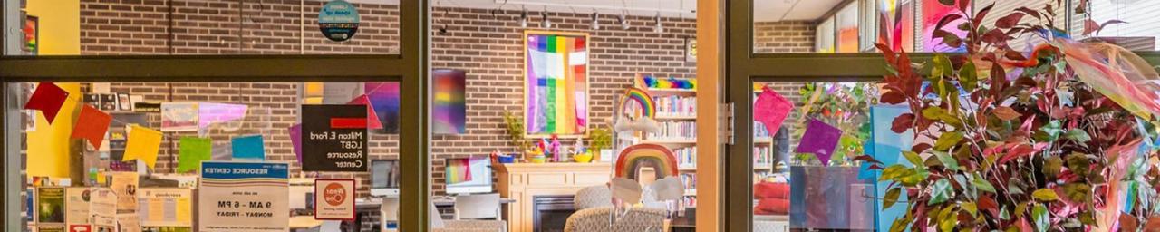 Looking through the door and glass windows of LGBT资源中心. It is bright and colorful inside, with a visible rainbow flag. Photo credit: Macayla with Lanthorn 2022